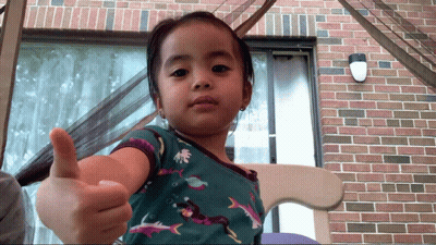 A Little Girl Is Giving A Thumbs Up Sign GIF
