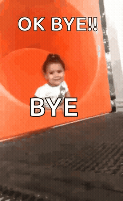 a little girl is going down an orange slide and says ok bye