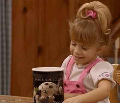 A Little Girl Is Holding A Can Of Ice Cream And Smiling GIF
