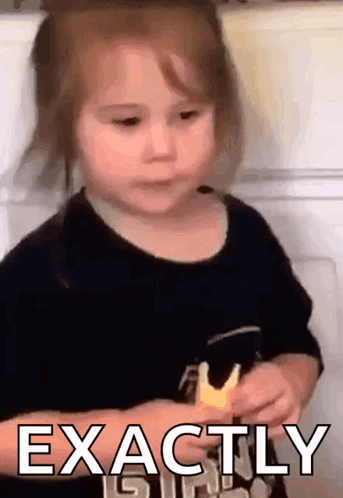 A Little Girl Is Holding A Piece Of Food And The Words Exactly Are Visible . GIF