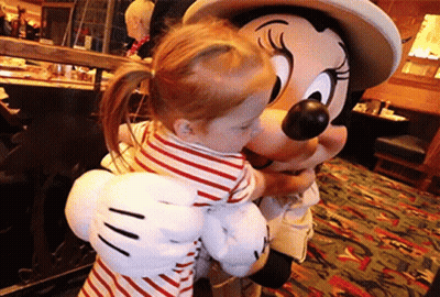 A Little Girl Is Hugging A Mickey Mouse Mascot GIF