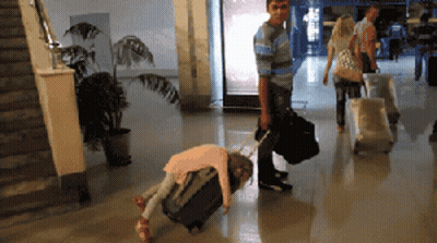 A Little Girl Is Laying On A Suitcase While A Man Pushes A Suitcase GIF