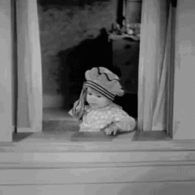 A Little Girl Is Looking Out Of A Window Wearing A Hat . GIF