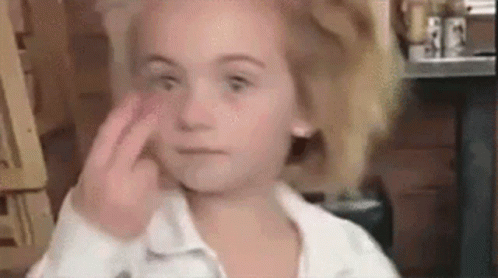 A Little Girl Is Making A Funny Face By Touching Her Face With Her Finger . GIF