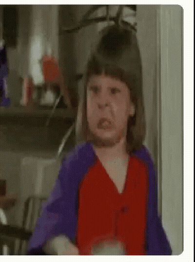 A Little Girl Is Making A Funny Face In A Kitchen . GIF