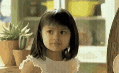 A Little Girl Is Making A Funny Face In Front Of A Window . GIF