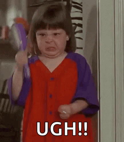 A Little Girl Is Making A Funny Face While Holding A Toy . GIF