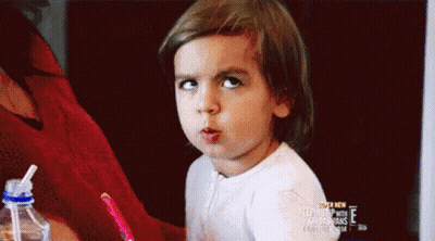 A Little Girl Is Making A Funny Face While Sitting At A Table . GIF