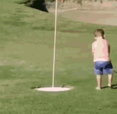 A Little Girl Is Playing Golf On The Green GIF