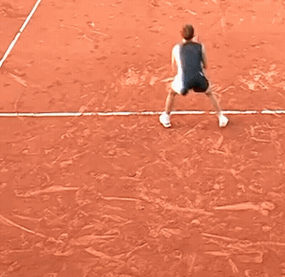A Little Girl Is Playing Tennis On A Clay Court GIF