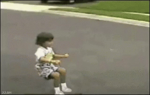 A Little Girl Is Riding A Scooter Down A Street . GIF