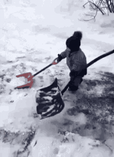 A Little Girl Is Shoveling Snow With A Shovel And A Bag . GIF