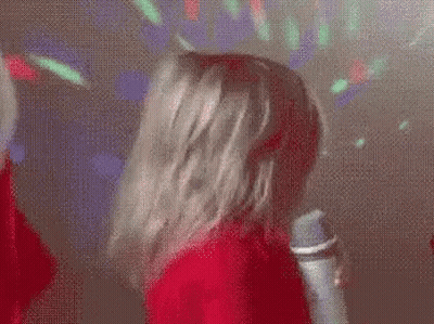 A Little Girl Is Singing Into A Microphone And Making A Face . GIF