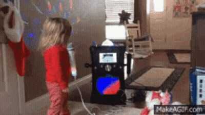 A Little Girl Is Singing Into A Microphone In Front Of A Karaoke Machine . GIF