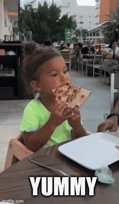 A Little Girl Is Sitting At A Table Eating A Slice Of Pizza . GIF