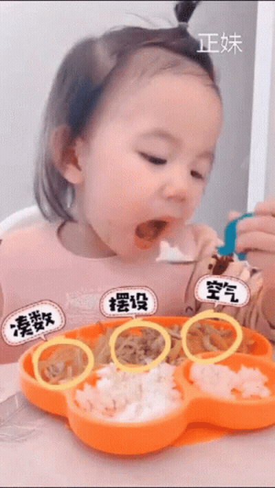A Little Girl Is Sitting At A Table Eating Food From A Flower Shaped Plate GIF