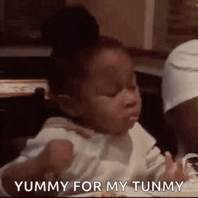 A Little Girl Is Sitting At A Table In A Restaurant Eating Food . GIF