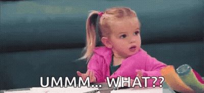 A Little Girl Is Sitting At A Table Making A Funny Face And Asking , `` Ummm ... What ? '' GIF