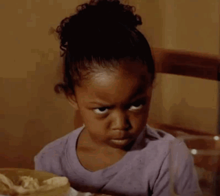 A Little Girl Is Sitting At A Table With A Bag Of Chips In Front Of Her GIF
