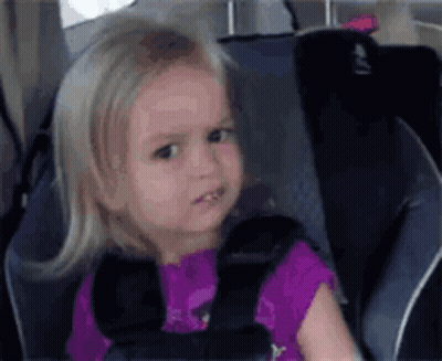 A Little Girl Is Sitting In A Car Seat Wearing A Seat Belt . GIF