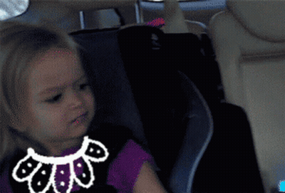 A Little Girl Is Sitting In A Car Seat With A Drawing Of A Cat On Her Shirt GIF