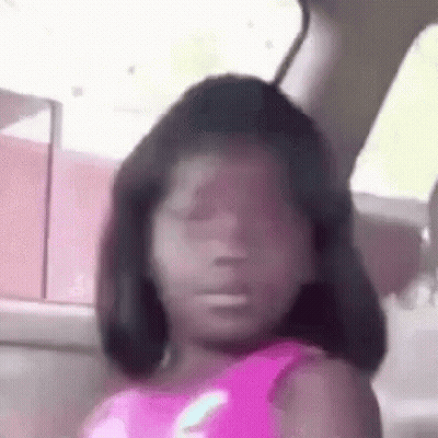A Little Girl Is Sitting In A Car With Her Eyes Closed And Making A Funny Face . GIF