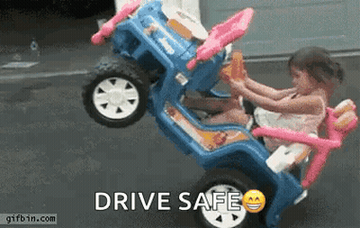 A Little Girl Is Sitting In A Toy Car With The Words Drive Safe Written On It . GIF