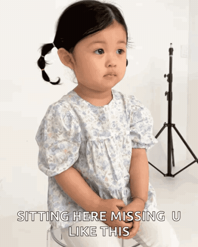 A Little Girl Is Sitting On A Clear Stool With The Words " Sitting Here Missing U Like This " Below Her GIF