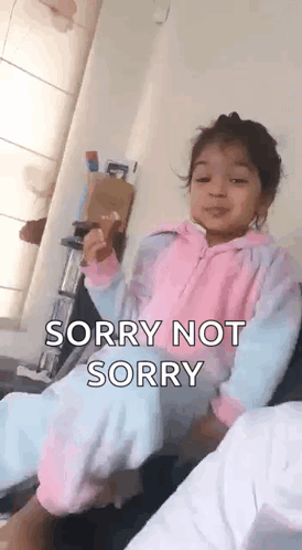 A Little Girl Is Sitting On A Couch And Making A Funny Face And Saying Sorry Not Sorry . GIF