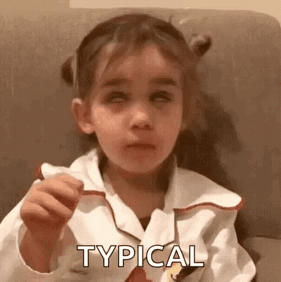 A Little Girl Is Sitting On A Couch And Making A Funny Face While Holding A Piece Of Food . GIF