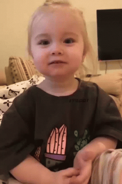 A Little Girl Is Sitting On A Couch Wearing A T-Shirt With A Cactus On It . GIF
