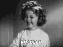 A Little Girl Is Smiling In A Black And White Photo And Says `` Rosebud '' . GIF