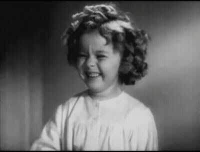 A Little Girl Is Smiling In A Black And White Photo . GIF