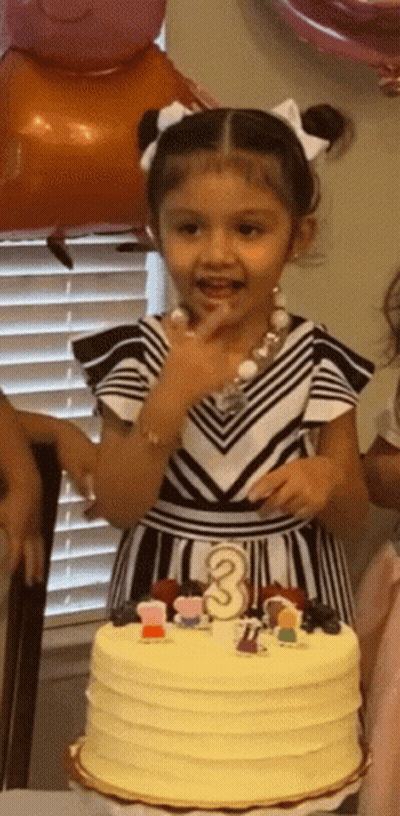 A Little Girl Is Standing In Front Of A Cake That Has The Number 3 On It GIF