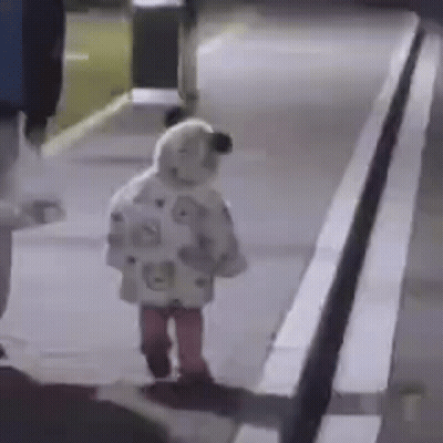 A Little Girl Is Walking Down A Sidewalk At Night Wearing A Sheep Costume . GIF