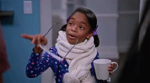 A Little Girl Is Wearing A Scarf And Holding A Cup Of Coffee And A Toothbrush . GIF