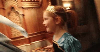 A Little Girl Is Wearing A Tiara And A Blue Dress While Standing Next To A Man . GIF