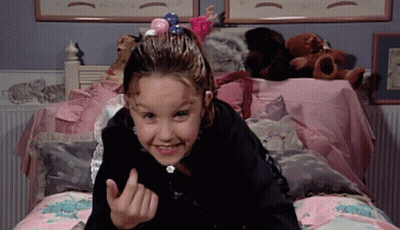 A Little Girl Laying On A Bed With Stuffed Animals On It GIF