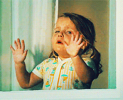 A Little Girl Looking Out Of A Window With Her Hands On The Glass GIF
