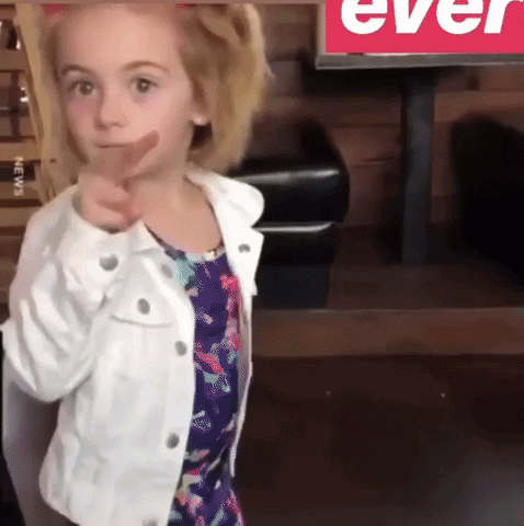 A Little Girl Pointing At The Camera In Front Of A Sign That Says " Ever " GIF