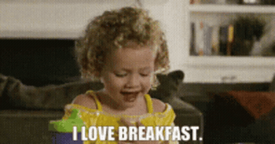 A Little Girl Says I Love Breakfast While Eating A Snack GIF