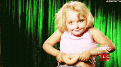 A Little Girl Shows Off Her Stomach In Front Of A Green Curtain That Says Tlc On It GIF