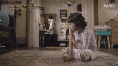 A Little Girl Sitting On A Rug With A Tvn Logo On The Wall Behind Her GIF