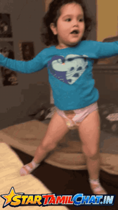 A Little Girl Wearing A Diaper And A Blue Shirt With A Heart On It Is Jumping In The Air GIF