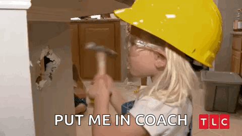 A Little Girl Wearing A Hard Hat And Safety Glasses Is Holding A Hammer In Front Of A Wall . GIF