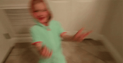 A Little Girl Wearing A Hoodie Is Standing In A Hallway GIF