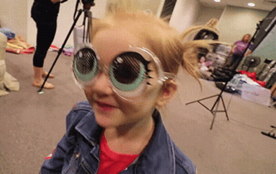 A Little Girl Wearing A Pair Of Glasses That Look Like Big Eyes . GIF