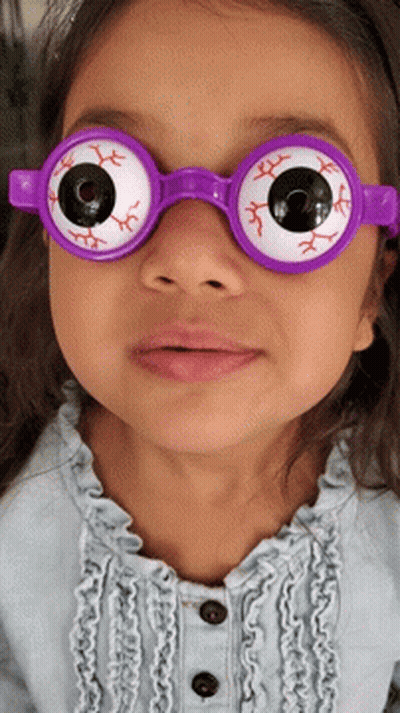 A Little Girl Wearing A Pair Of Purple Glasses With Fake Eyes GIF