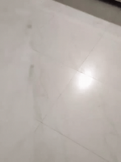 A Little Girl Wearing A Pink Jacket Is Peeking Out From Behind A White Wall GIF