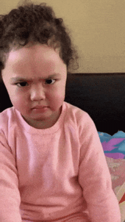 A Little Girl Wearing A Pink Shirt Is Making A Funny Face GIF